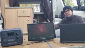 Fredo Brico teste la station électrique BLUETTI Elite 100 V2 devant son fourgon aménagé pour alimenter une télévision et un ordinateur portable en autonomie.