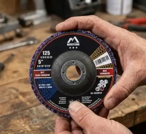 Gros plan sur les mains d'un artisan présentant un disque de décapage CSD violet Merryland de 125 mm au-dessus d'un établi d'atelier.