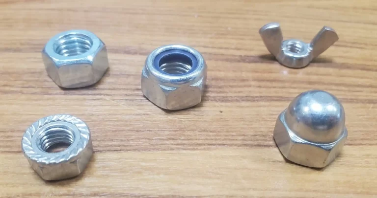 Assortiment d'écrous réels sur un établi pour apprendre à choisir un écrou de fixation.