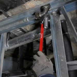 Utilisation d'une clé à béquille sous l'évier pour dévisser l'écrou de fixation d'un robinet grippé