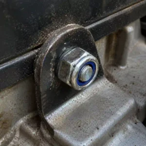 Gros plan d un écrou M8 Nylstop ( écrou frein) sécurisant une fixation sur un carter de tondeuse thermique.